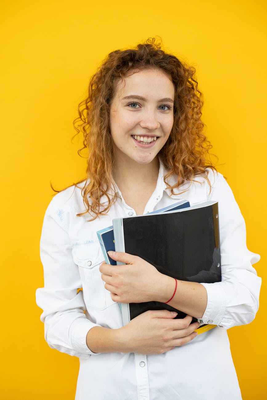 cheerful woman with folder and textbook